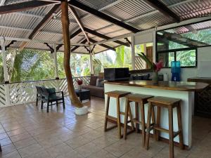 a kitchen with a bar with stools and a living room at Arrecife Punta Uva - Hospedaje, bar y restaurante - Frente al mar in Punta Uva