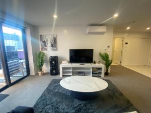 a living room with a table and a tv at Central City Views In Heart of Central Chch by Stadium in Christchurch
