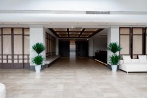 a lobby with white furniture and palm plants at vangvieng THAVIKUN HOTEL in Vang Vieng