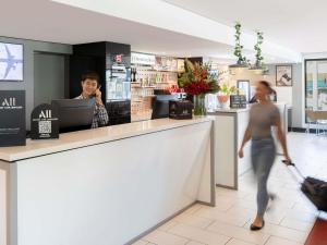a man talking on a cell phone behind a counter in a store at ibis Newcastle in Newcastle
