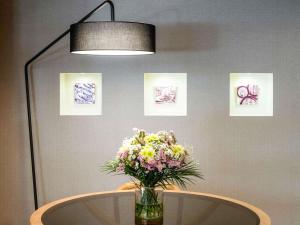 a vase of flowers on a table with pictures at Hotel Mercure Porto Gaia in Vila Nova de Gaia