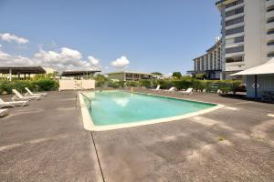 a large swimming pool with chairs and a building at Hilo Lagoon Centre - 4BR Condos - Sleeps 12 in Hilo