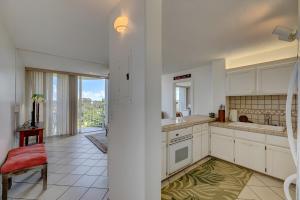 a kitchen with white cabinets and a red chair at Hilo Lagoon Centre - 4BR Condos - Sleeps 12 in Hilo