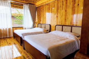 two beds in a room with wooden walls and a window at Sapa Rose Garden Resort in Sapa