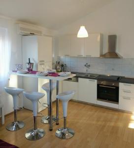 a kitchen with a table and bar stools in it at Apartman Lana in Klimno