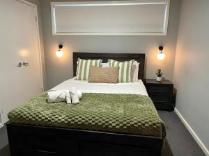 a bedroom with a large bed with a green blanket at The Snug Suite in Cooranbong