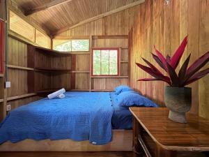 a bedroom with a blue bed in a wooden cabin at Sabalo Lodge Tours and Cabins in Sierpe