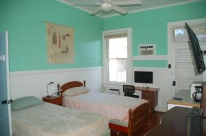 a bedroom with two beds and a desk and a window at Hale Naalehu LLC Bed and Breakfast in Naalehu