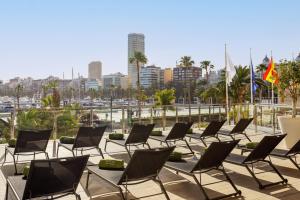 a row of chairs sitting on a patio with a harbor at Meliá Alicante in Alicante