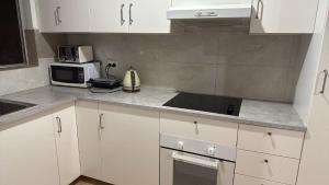 a kitchen with white cabinets and a microwave at Room 1 Bright Spacious Room Walk to Shops in Kelmscott