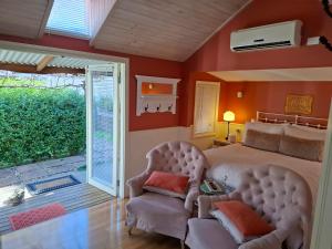 a bedroom with a bed and a chair and a sliding glass door at Bella Rouge Cottage in Bright