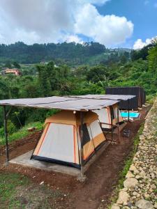 a group of tents with a roof on a hill at Cihulu Budget Glamping in Tengahgirang