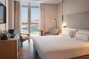 a hotel room with a large bed and a large window at Meliá Maria Pita in A Coruña