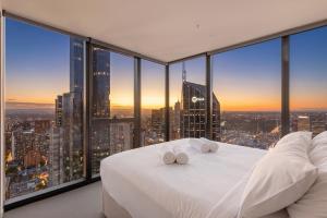 a bedroom with a white bed and large windows at Park Avenue - UNO Melbourne in Melbourne