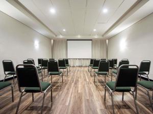 a conference room with chairs and a projector screen at ibis Betim in Contagem