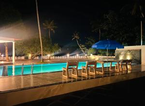 a table with chairs and an umbrella next to a swimming pool at Lavilla Lake Resort And Restaurant in Kollam