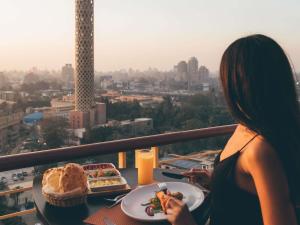 a woman sitting at a table with a plate of food at Novotel Cairo El Borg in Cairo
