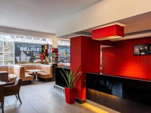 a restaurant with a bar with a red wall at ibis Belfast Queens Quarter in Belfast