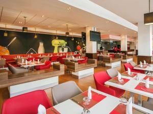 a restaurant with red chairs and tables and a tv at Ibis Lagos Ikeja in Ikeja
