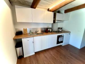 a kitchen with white cabinets and a wooden floor at Suite Église in Veynes