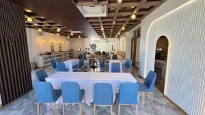 a dining room with a white table and blue chairs at The Room Hotel in Ban Nong Puk