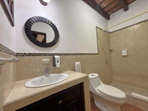 a bathroom with a sink and a toilet and a mirror at Alana Hotel By ISH in Antigua Guatemala
