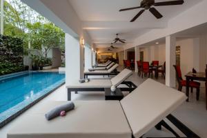 a pool room with white furniture and a swimming pool at THE RIVERFRONT CENTRAL Hotel in Siem Reap