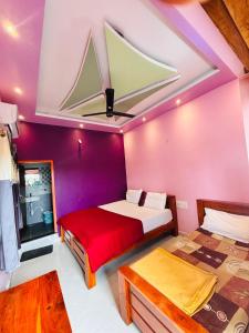 a bedroom with two beds in a room with purple walls at Hampi Icon Palace in New Hampi