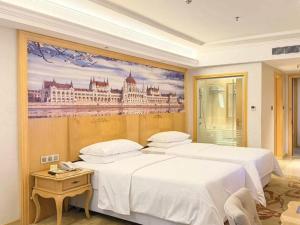 two beds in a room with a painting on the wall at Guangna Hotel in Huizhou +289 photos