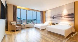 a hotel room with two beds and a large window at Qingdao Elegance Hotel in Qingdao +69 photos