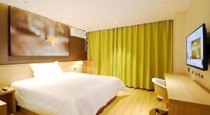 a bedroom with a large white bed and a television at IU Hotel Baoding Goverment Shidai in Baoding