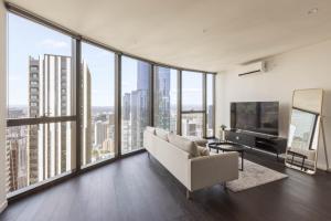a living room with a couch and large windows at Park Avenue - UNO Melbourne in Melbourne