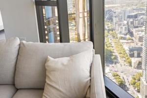 a couch with a pillow in front of a window at Park Avenue - UNO Melbourne in Melbourne
