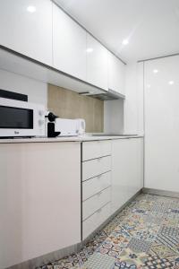 een keuken met witte kasten en een magnetron bij Alfama Apartment with River view in Lissabon +12 foto's