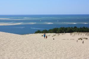 eine Gruppe von Menschen, die an einem Sandstrand spazieren in der Unterkunft Le Chai O Soleils in Mortagne-sur-Gironde