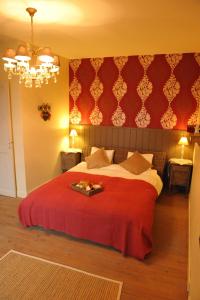 um quarto com uma cama grande e um cobertor vermelho em Le Chai O Soleils em Mortagne-sur-Gironde