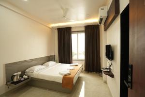 a hotel room with a bed and a television at Hotel Shreyash in Solapur
