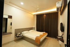 a hotel room with a bed and a television at Hotel Shreyash in Solapur