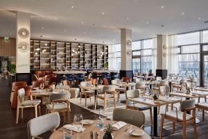 a restaurant with tables and chairs and a bar at INNSiDE by Meliá Bremen in Bremen