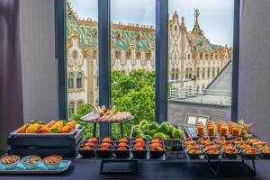 a buffet of fruits and vegetables in front of a window at Hotel President Budapest, Affiliated by Meliá in Budapest +30 photos