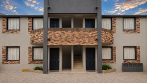 a brick building with black doors and a balcony at VIRREYES418 extended apartments in Los Valdeses