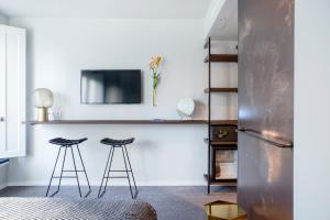 a living room with two stools and a tv at The Fritz Düsseldorf Königsallee in Düsseldorf