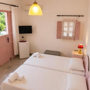 a bedroom with two beds and a tv and a window at Porto Sikinos Hotel in Alopronia +17 photos