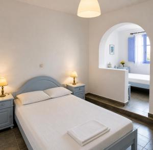 a bedroom with a white bed with two night stands at Porto Sikinos Hotel in Alopronia