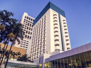 a large building with palm trees in front of it at Mercure Uberlândia Plaza Shopping in Uberlândia