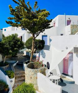 a view of a building with a tree and chairs at Porto Sikinos Hotel in Alopronia