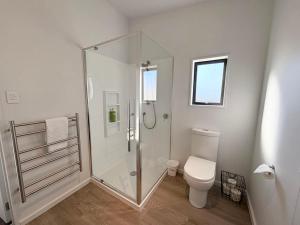 a white bathroom with a shower and a toilet at The Bach in Lake Tekapo +26 photos