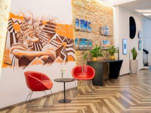 a lobby with two red chairs and a painting on the wall at Mercure Firenze Centro in Florence