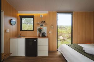 a bedroom with a bed and a kitchen with a refrigerator at One Gaea by Tiny Away in Rainbow Flat