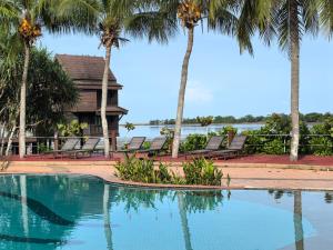 a swimming pool with palm trees and a house at Langkawi Lagoon Floating Resort 03 in Kampung Padang Masirat